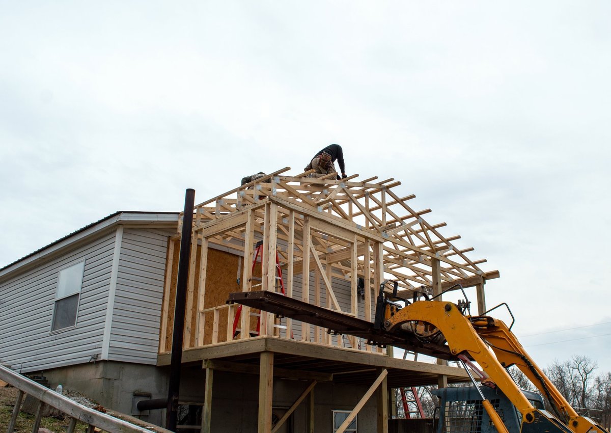 Carpenters framing a new roof on a home addition under construction.