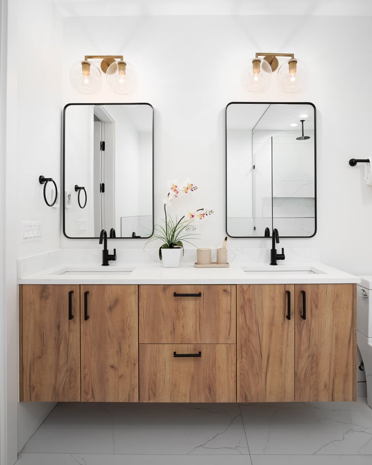 Floating wood vanity cabinet with marble countertop and black faucets.