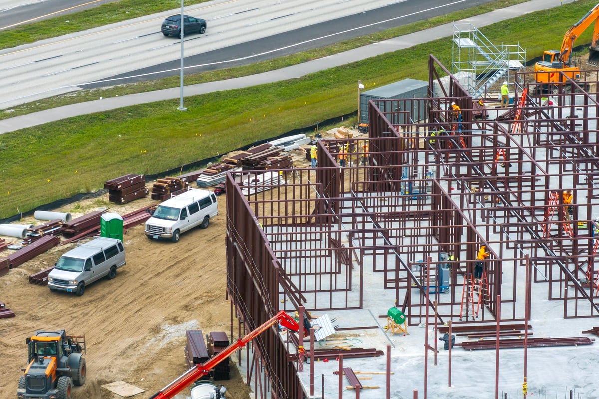Workers assembling metal frame building at industrial construction site. Housing development in America. Real estate market in the USA.