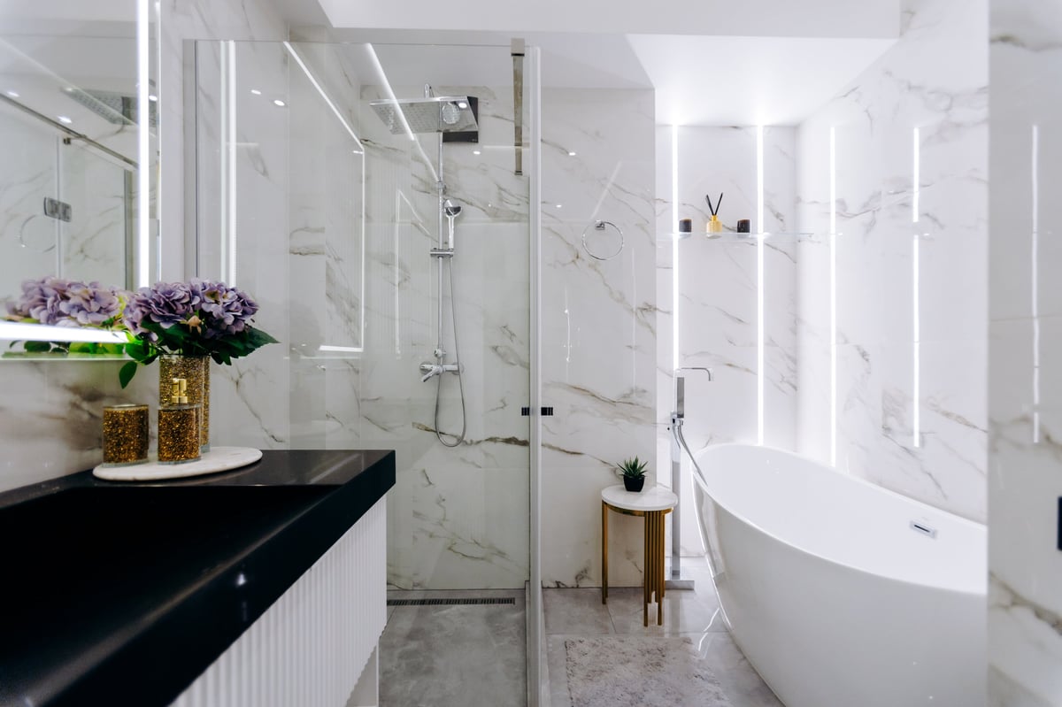 The bathroom features a cozy bathtub, a functional sink, a spacious shower and an elegantly designed mirror