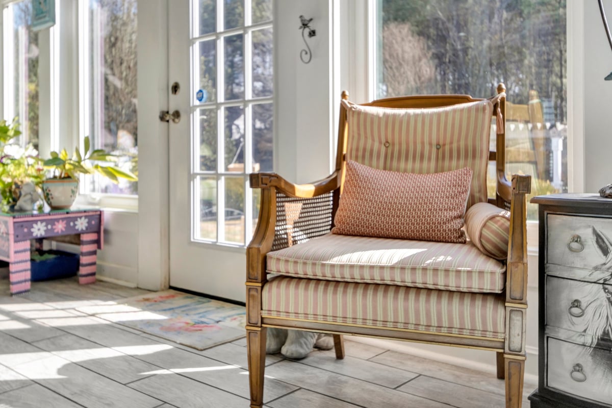 A comfortable chair in a bright sunroom surrounded by windows and natural light.