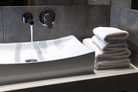 Modern chrome wall-mounted bathroom faucet and sink with easy-to-use controls.