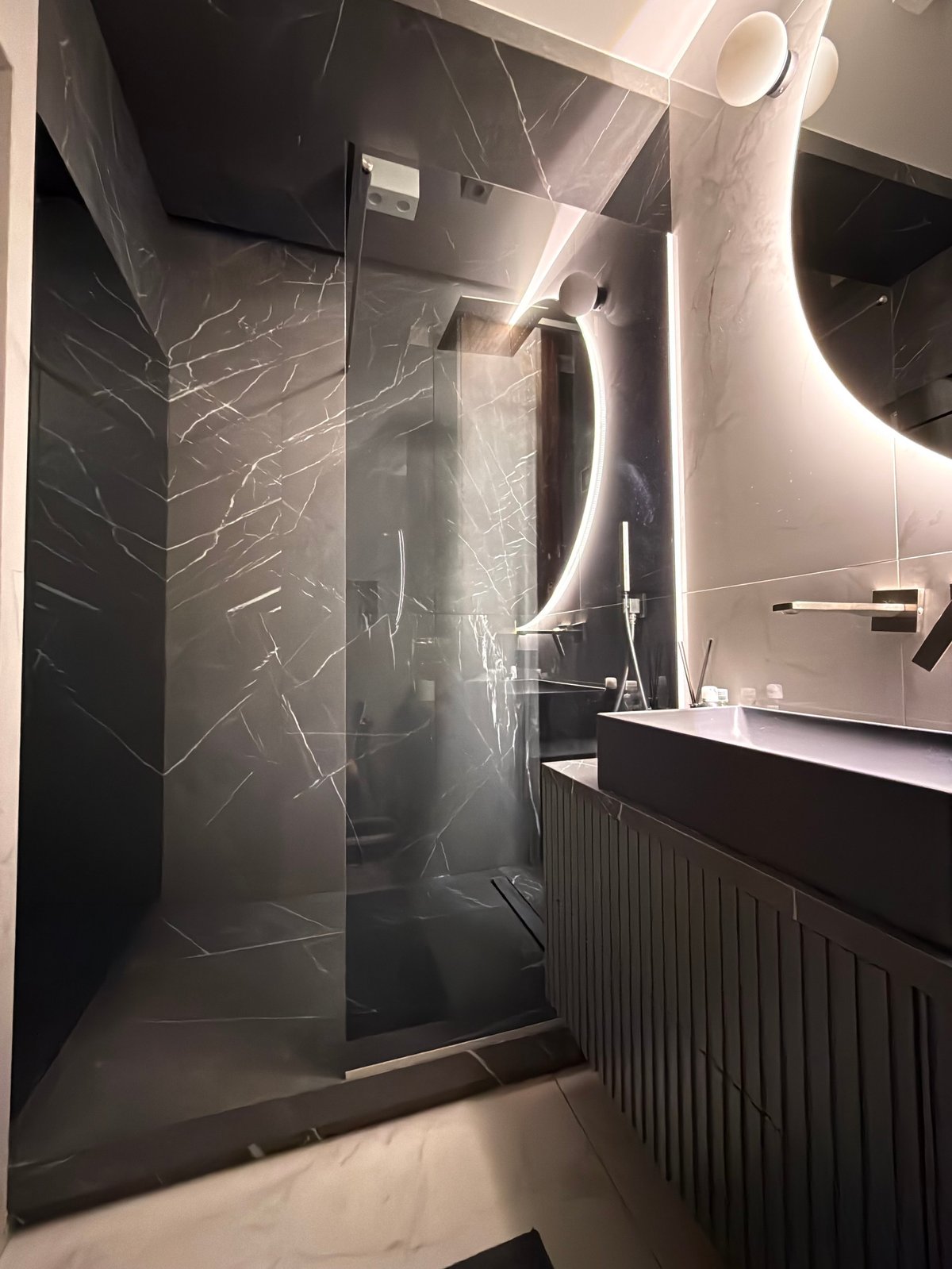 Bathroom remodel in Toledo Ohio featuring a marble tile walk-in shower, custom vanity, and backlit mirror by Just Ask Home Improvement.