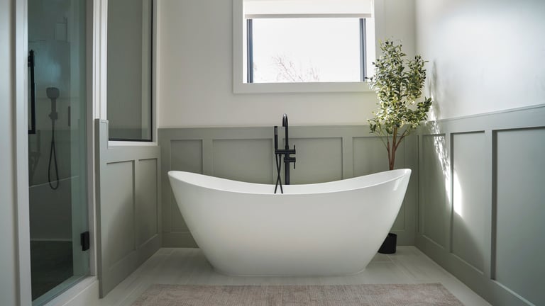 Modern freestanding soaking tub with floor-mounted matte black faucet.