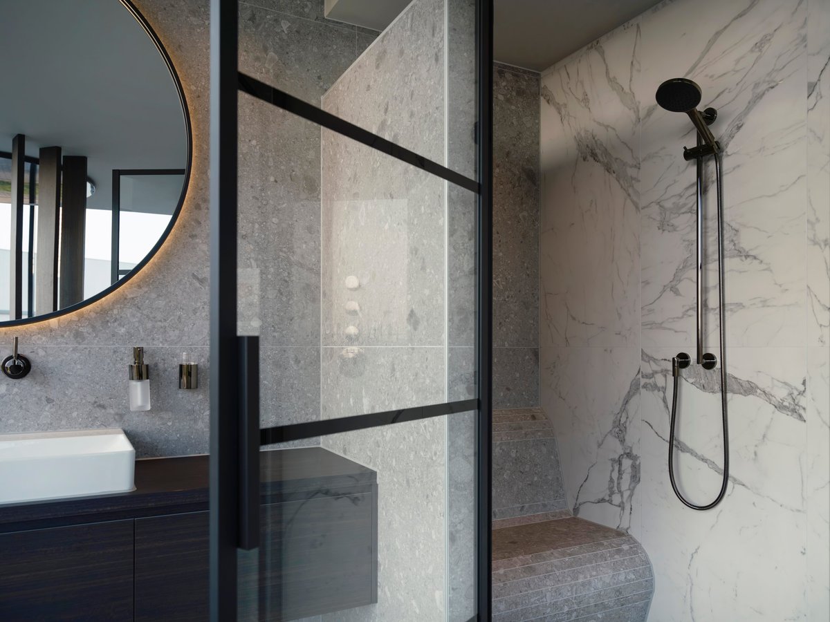 Bathroom remodel in Perrysburg Ohio with a marble walk-in shower behind black-framed glass and a vessel sink vanity