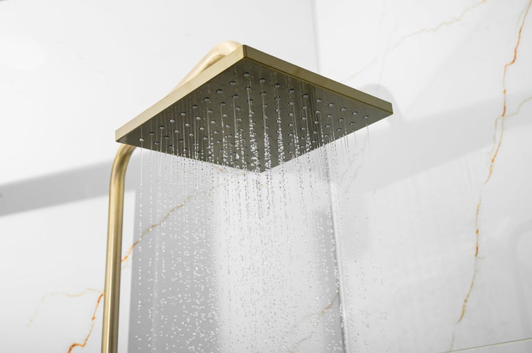 Rain showerhead in modern marble bathroom with gold hardware.