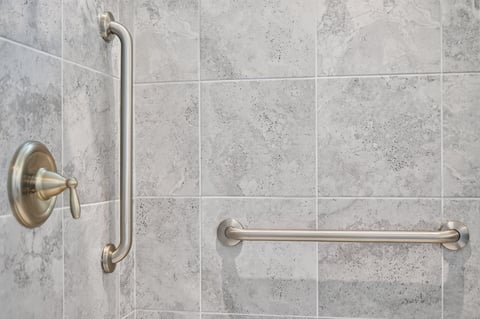 Multiple grab bars installed in tile shower for safety and stability.