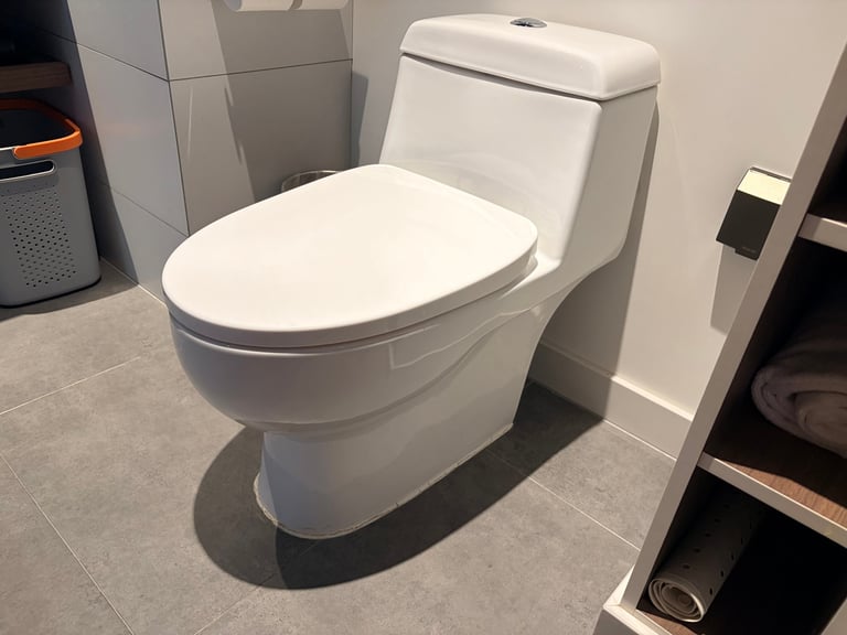Modern sleek ceramic toilet in clean minimal bathroom with neutral tile.