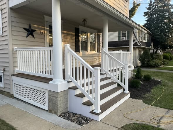 White painted front porch posts, spindle railing and painted porch steps on a two-story house with a black star wall decoration