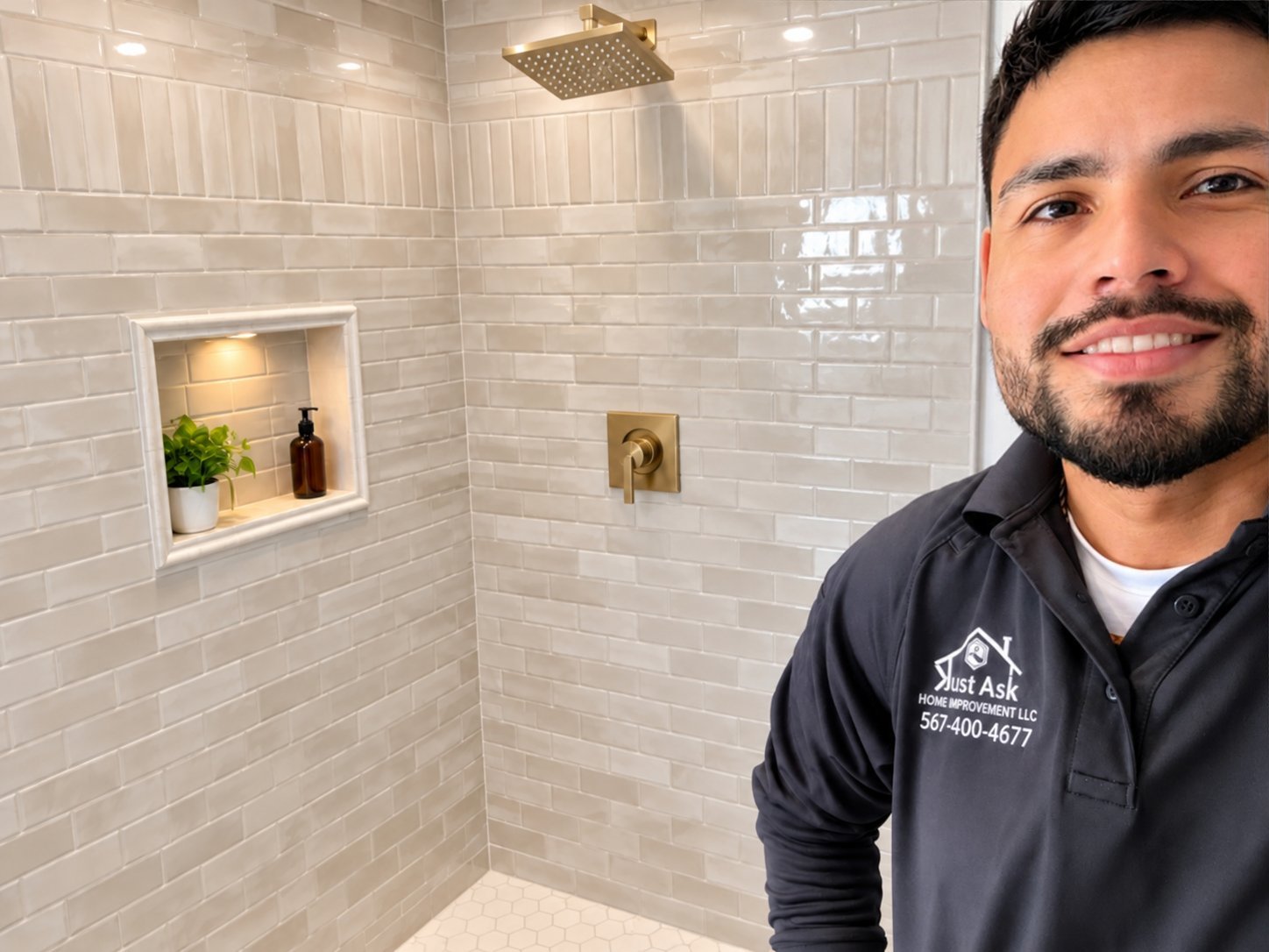 Man in dark work jacket posing in modern bathroom with white subway tile shower, gold fixtures, and recessed niche