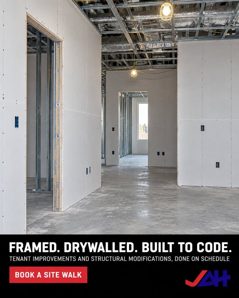 Empty commercial interior with newly framed drywall walls, exposed ceiling, concrete floor, and pendant lights during construction renovation