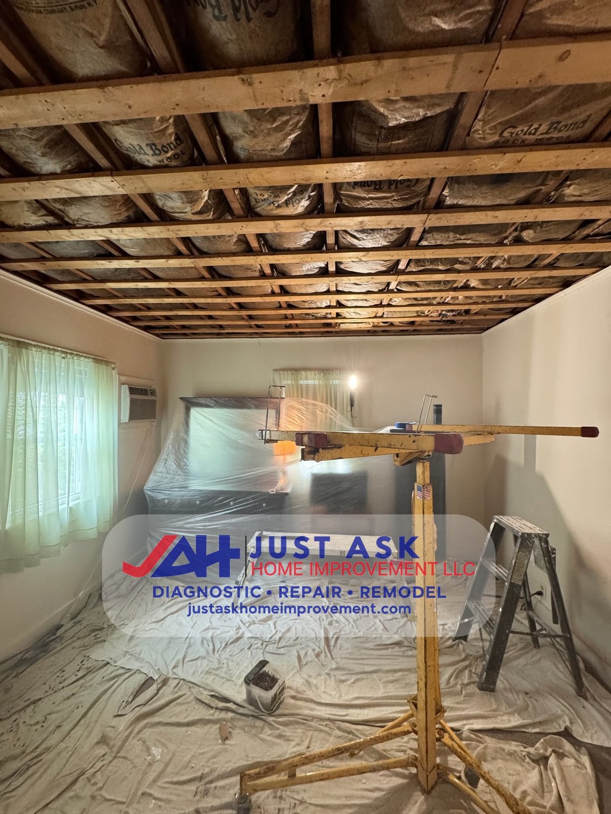 Exposed ceiling joists, drop cloths and containment during damaged drywall removal in a residential room